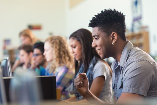 African American college student smiling while using computer in library