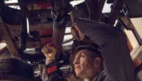 Mechanic using socket wrench while working on a chassis.