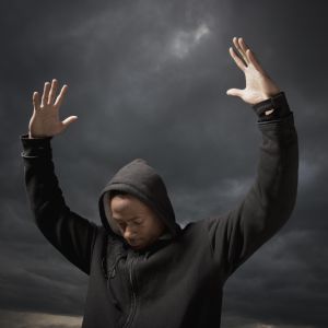 African man with arms raised, storm clouds in distance