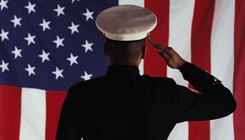 Man in U.S. Marine Corps uniform saluting American flag