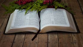 Opened Holy Bible with Christmas Garland on wood plank board