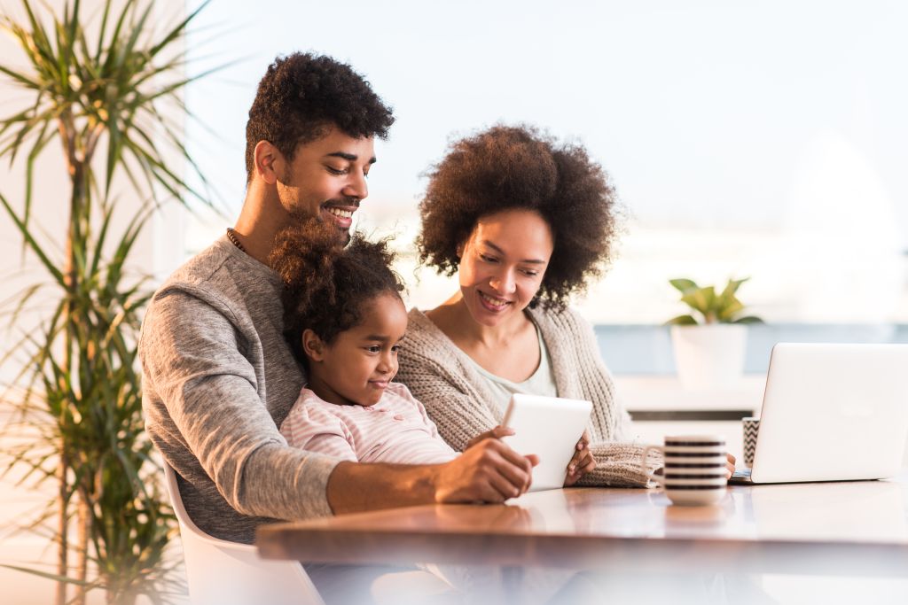 Happy African American family using digital tablet together.