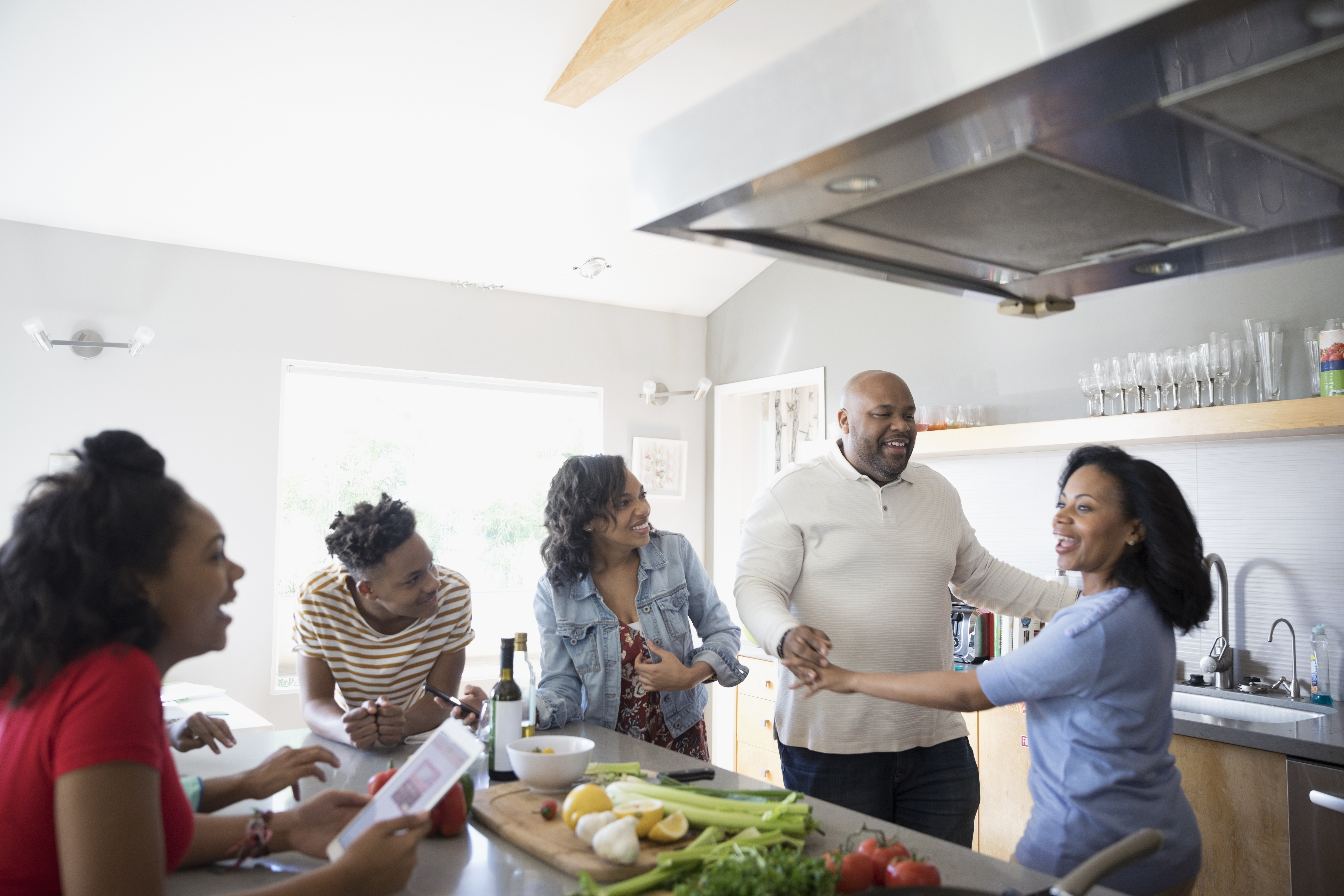 African American parents dancing and cooking with children in kitchen