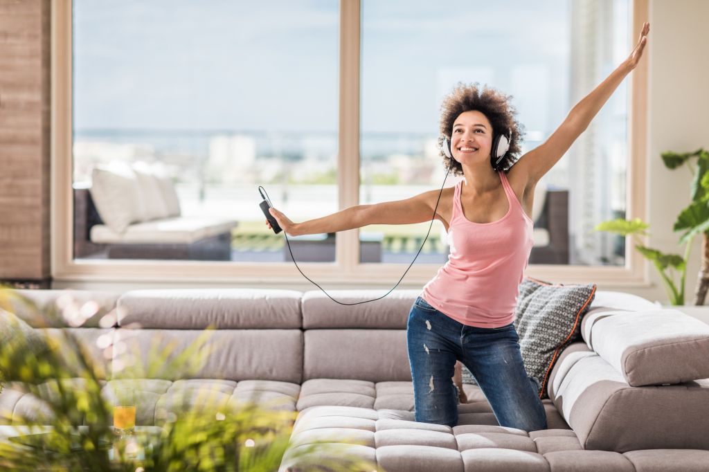 Carefree black woman enjoying in great music over MP3 player at home.