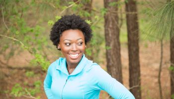 One African descent woman takes break from running in neighborhood park.