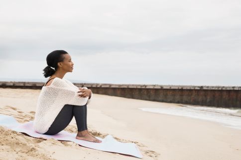 Serene woman sitting beach blanket looking at view