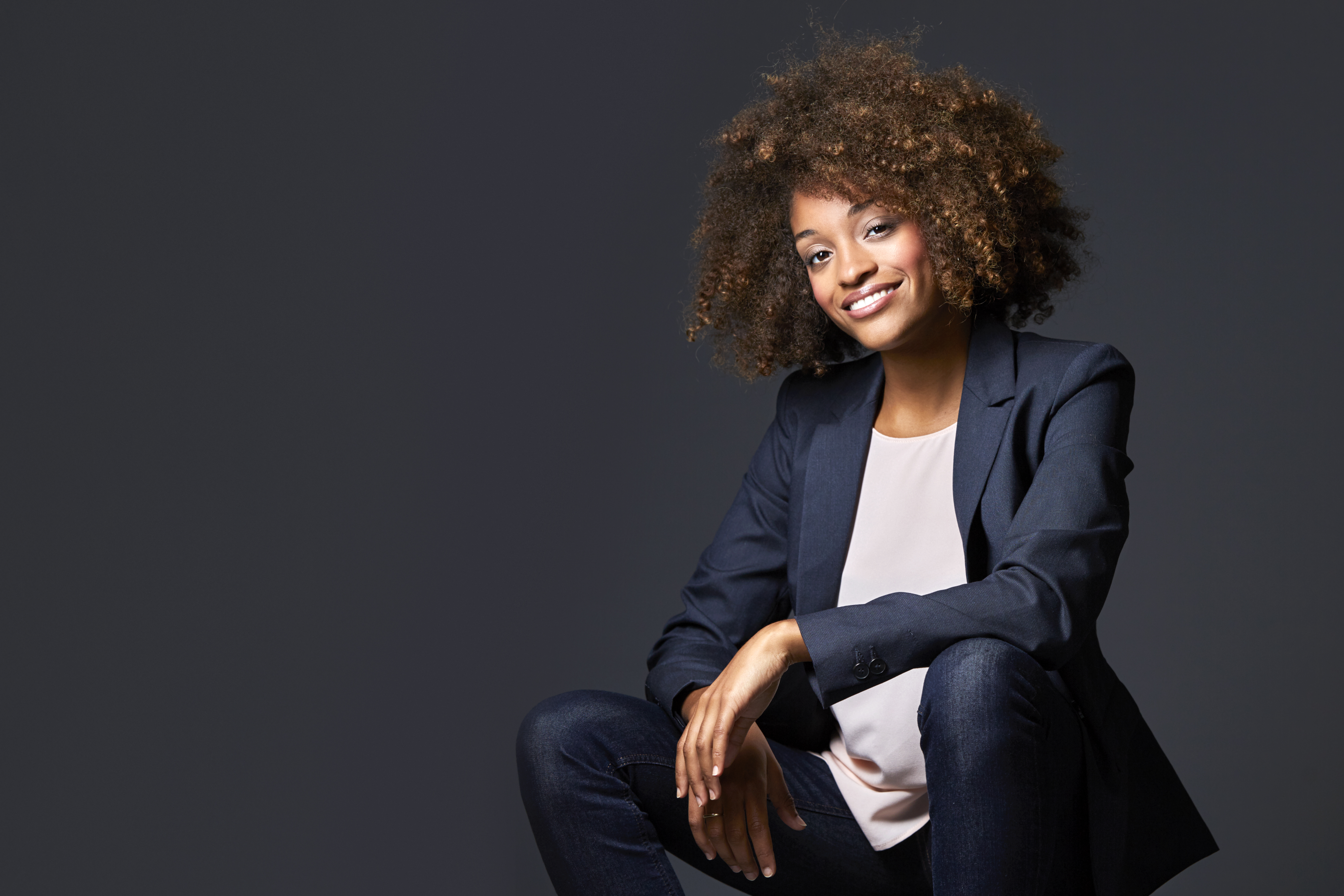 Businesswoman sitting against gray background