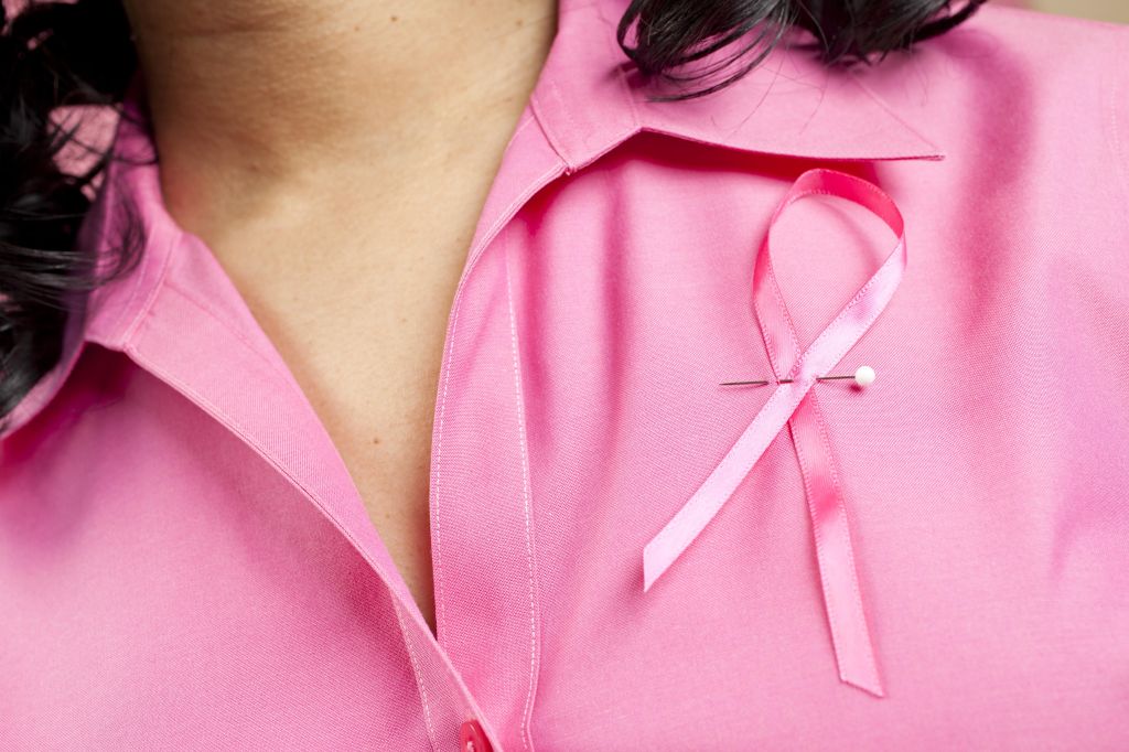 Woman wearing pink breast cancer ribbon on her blouse.