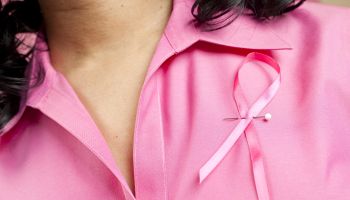Woman wearing pink breast cancer ribbon on her blouse.