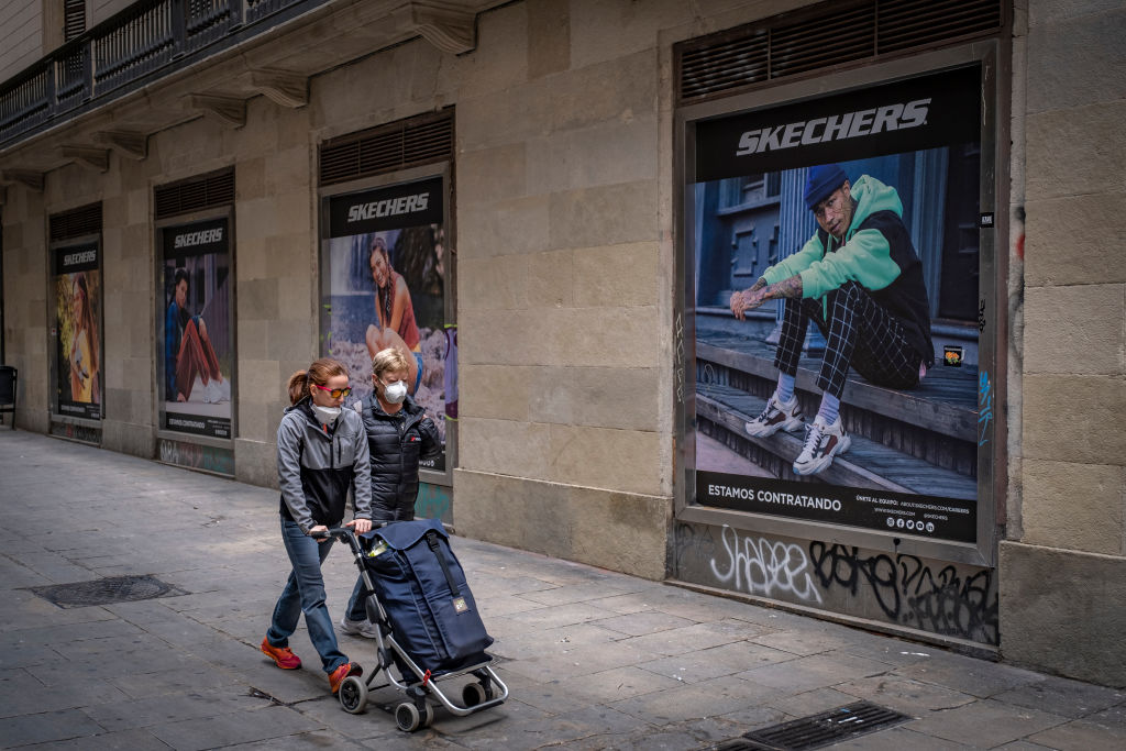 Women walking with a shopping cart along central shopping...