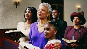 Family Standing in Church Pews Holding Bibles and Listening to a Service