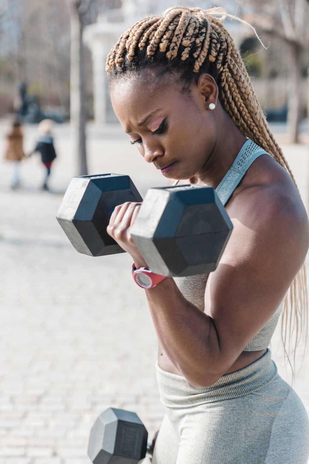 Black female athlete doing exercises with dumbbells on street