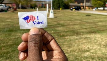 A black man holding a vote sticker