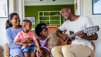 Father playing guitar to his family at home