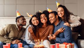 Joyful multicultural friends hugging bday lady celebrating and partying indoor