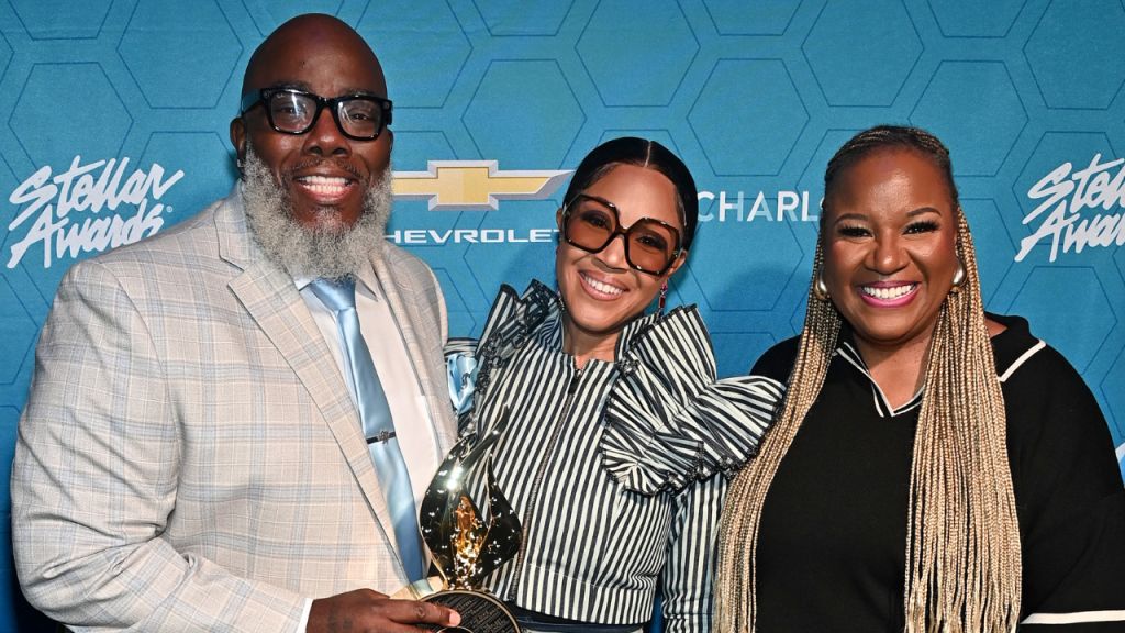 Three smiling people posing in front of a Chevrolet backdrop at the Stellar Awards event.